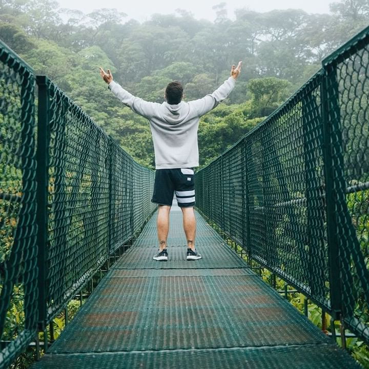 Man posing on a suspension bridge in the woods near Ficus Lodge