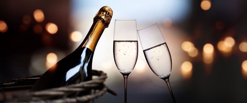 Champagne bottle in a wicker basket and two clinking flutes at The Diplomat Resort