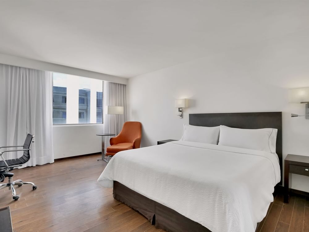 Orange couch facing a bed with city view in Superior Room, 1 King at Fiesta Inn Insurgentes Sur