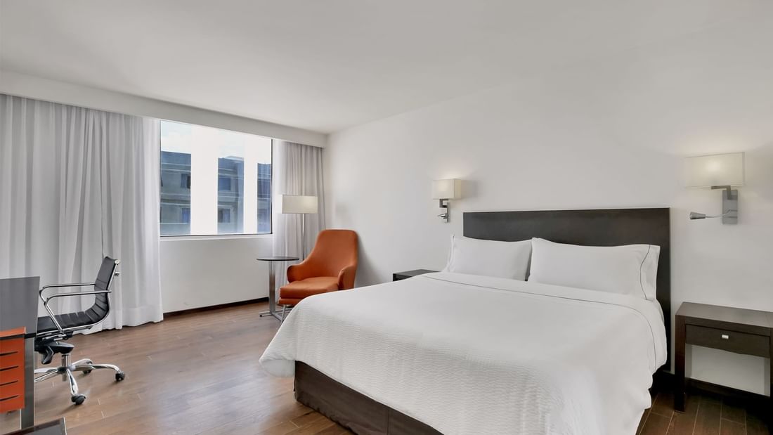 Orange couch facing a bed with city view in Superior Room, 1 King at Fiesta Inn Insurgentes Sur