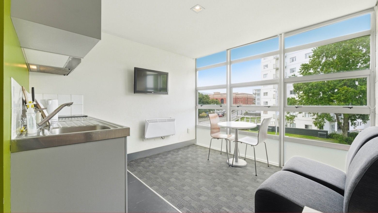 Modern kitchen and living space with large windows overlooking trees at Student Living Auckland - Beach.