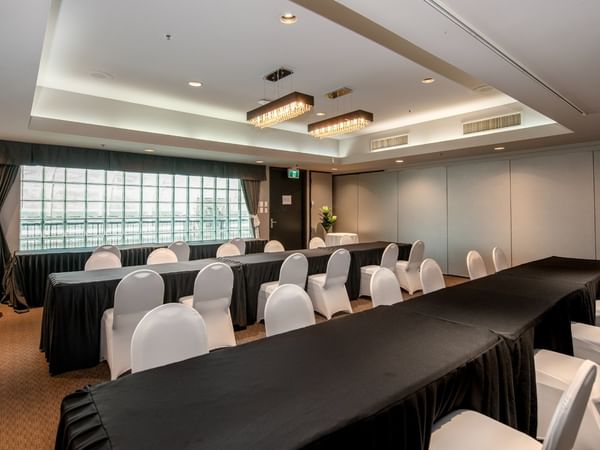Conference room with long tables, white chairs and windows