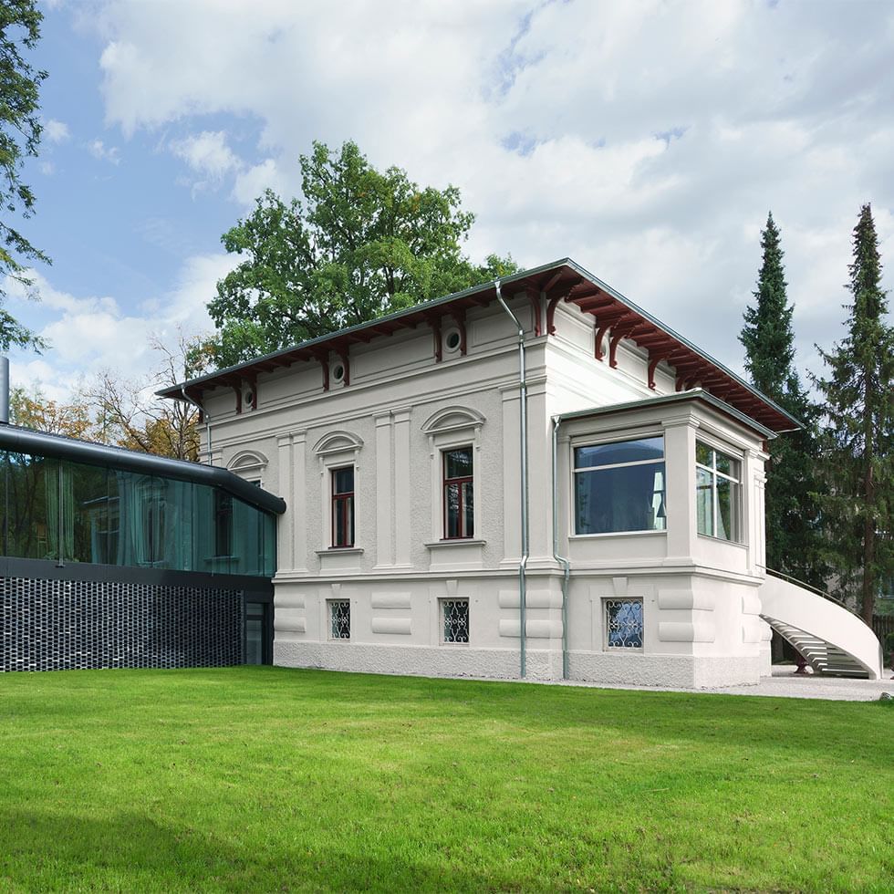 Exterior view of a villa with classical design and modern glass extension at Falkensteiner Hotel Kronplatz