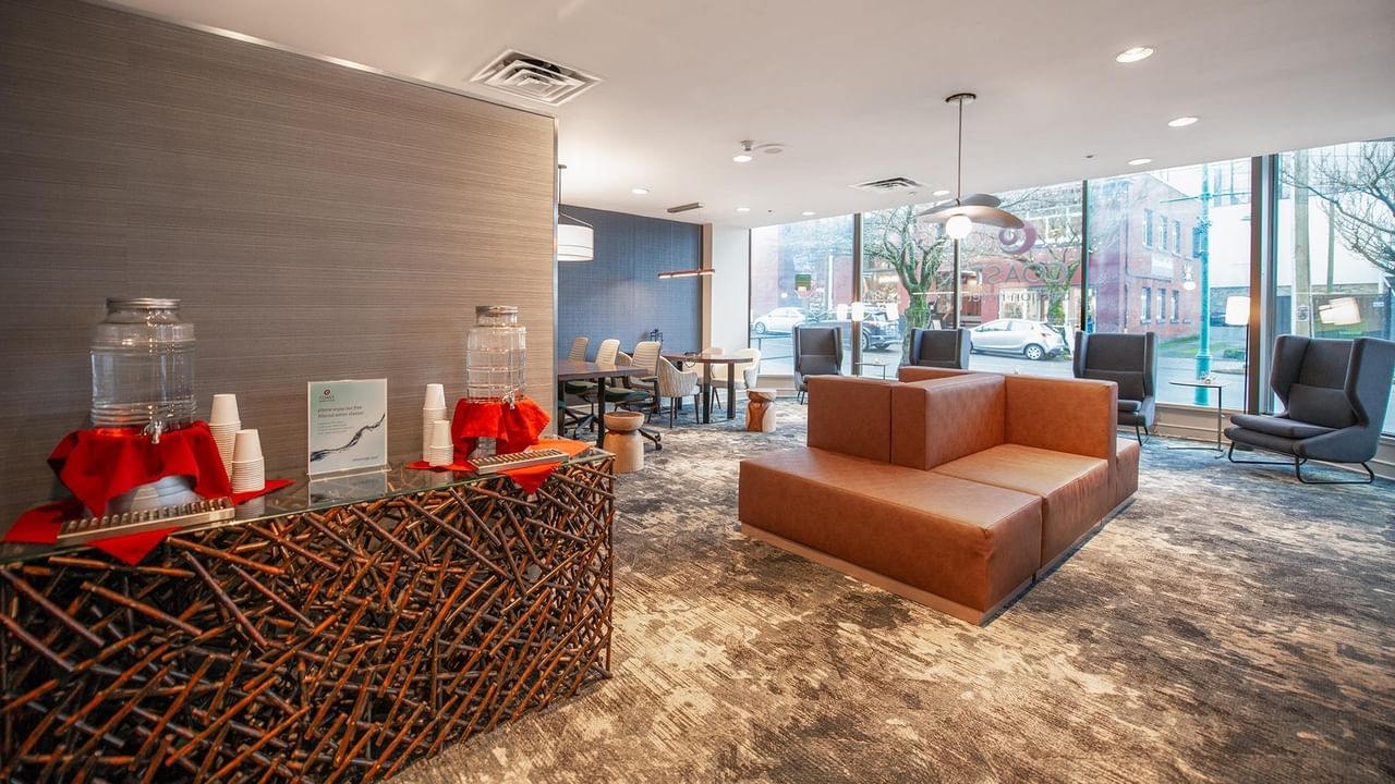 Elegant lounge area with a brown couch, large windows, and a decorative counter at Coast Bastion Hotel.