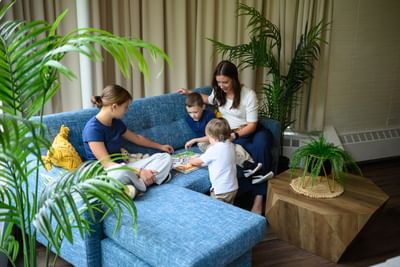Mother and three children sitting on a blue sectional sofa playing a fun board game together at Rodd Moncton