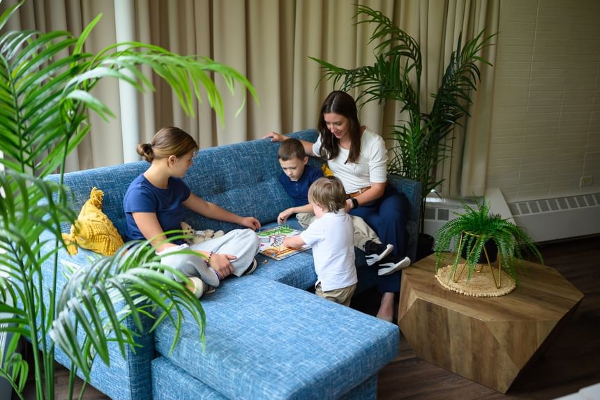 Mother and three children sitting on a blue sectional sofa playing a fun board game together at Rodd Moncton