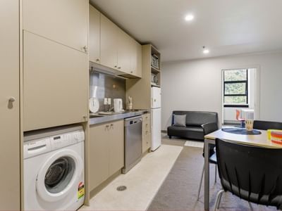 Modern kitchen with integrated appliances and a dining area in a hotel suite.