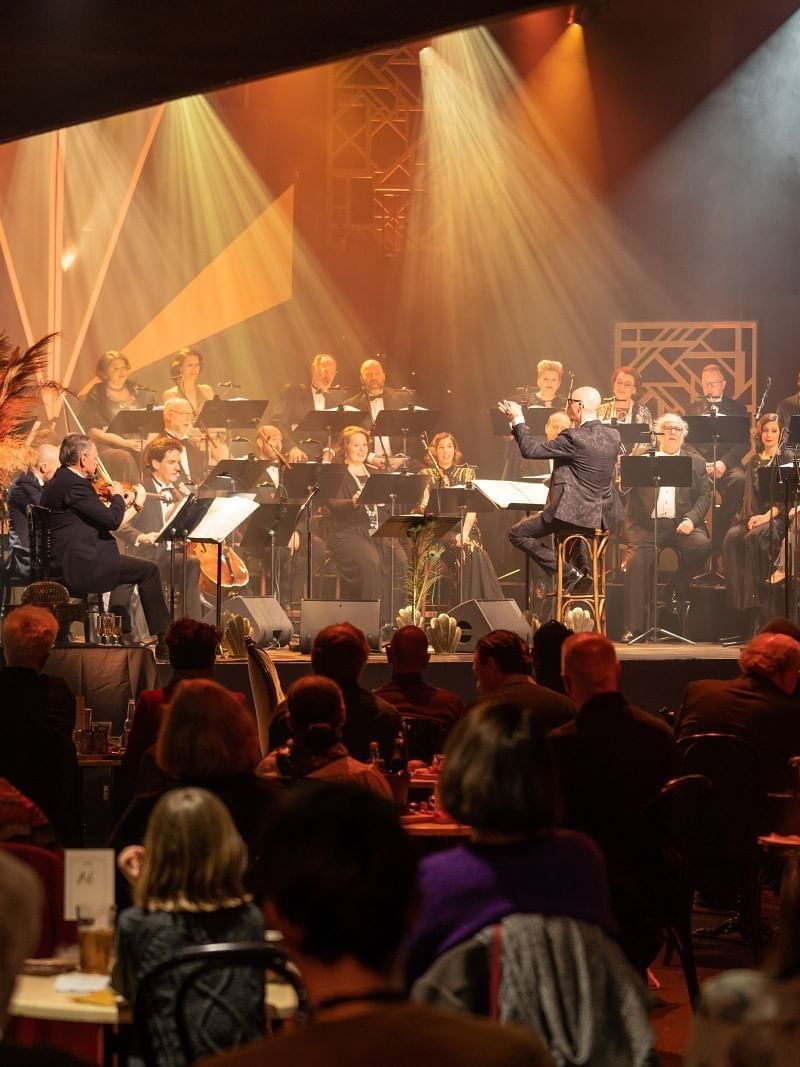 Musicians performing on stage under spotlights in front of an audience near Warwick Grand Place Brussels