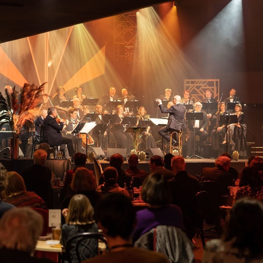 Musicians performing on stage under spotlights in front of an audience near Warwick Grand Place Brussels