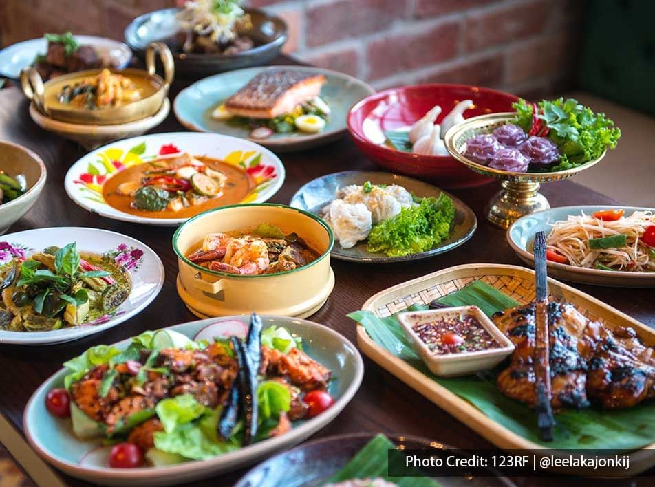 Diverse culinary spread with meats, curry vegetables and rice noodles on a dining table - Lexis Port Dickson