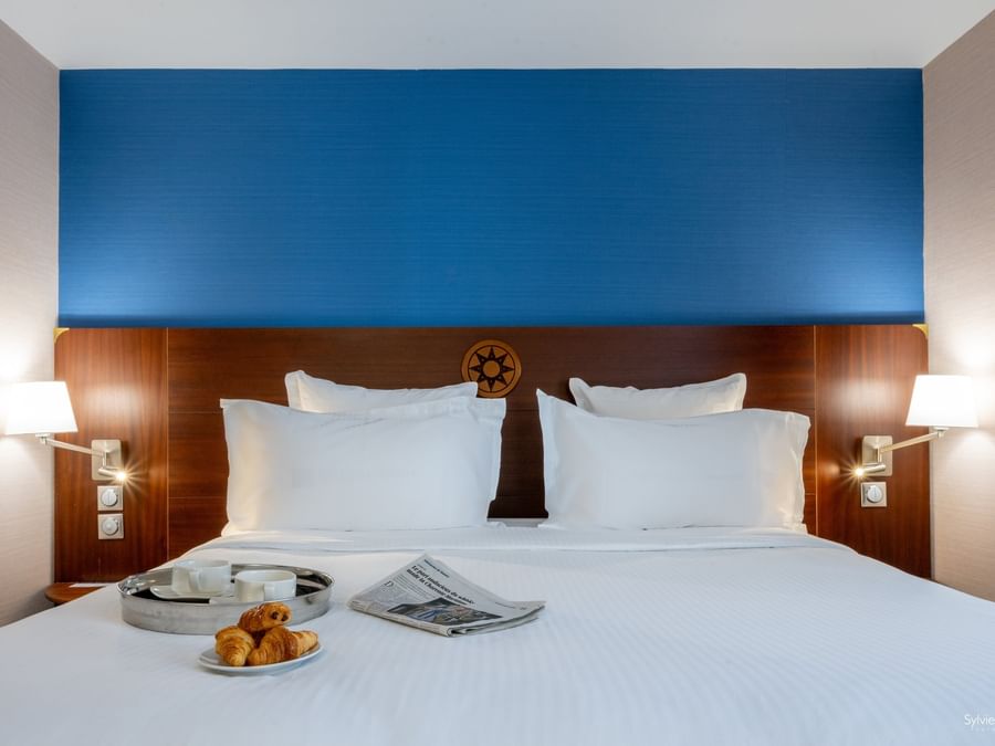 Chambre élégante avec lits, oreillers, éclairage, et plateau de petit-déjeuner à Hôtel Le Yachtman.
