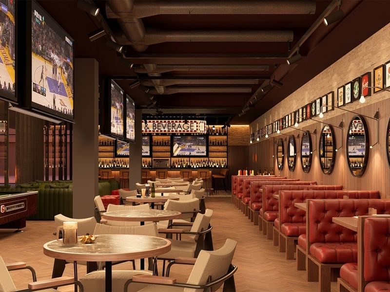 Bar deportivo moderno en Fiesta Americana Funeeq con cabinas rojas de cuero y varias TVs mostrando partidos de baloncesto