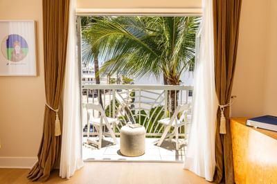 Cozy room opening onto a balcony with white chairs at The Savoy Hotel & Beach Club