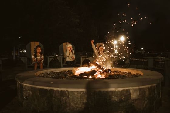 Outdoor fire pit with sparks flying and people around in The Lodge at Schroon Lake