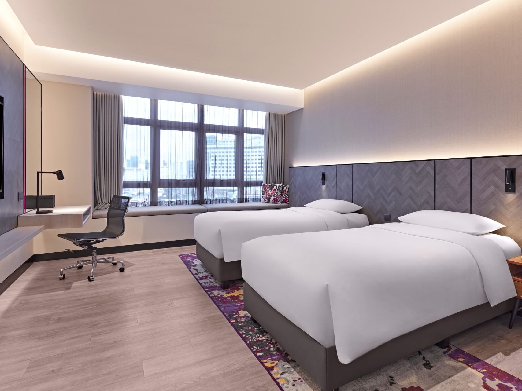 Spacious Deluxe Twin Room at Orchid Hotel Singapore with two single beds, a window bench and contemporary furnishings.