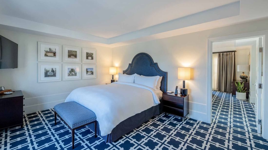 Penthouse featuring a large king bed, elegant headboard, and distinctive patterned carpet at El Prado Hotel