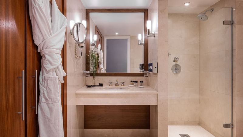 Bathroom vanity area with a mirror in Junior suite at Warwick Brussels