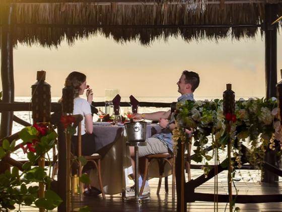 A couple enjoying dinner while smiling at each other at Plaza Pelicanos Club Beach Resort