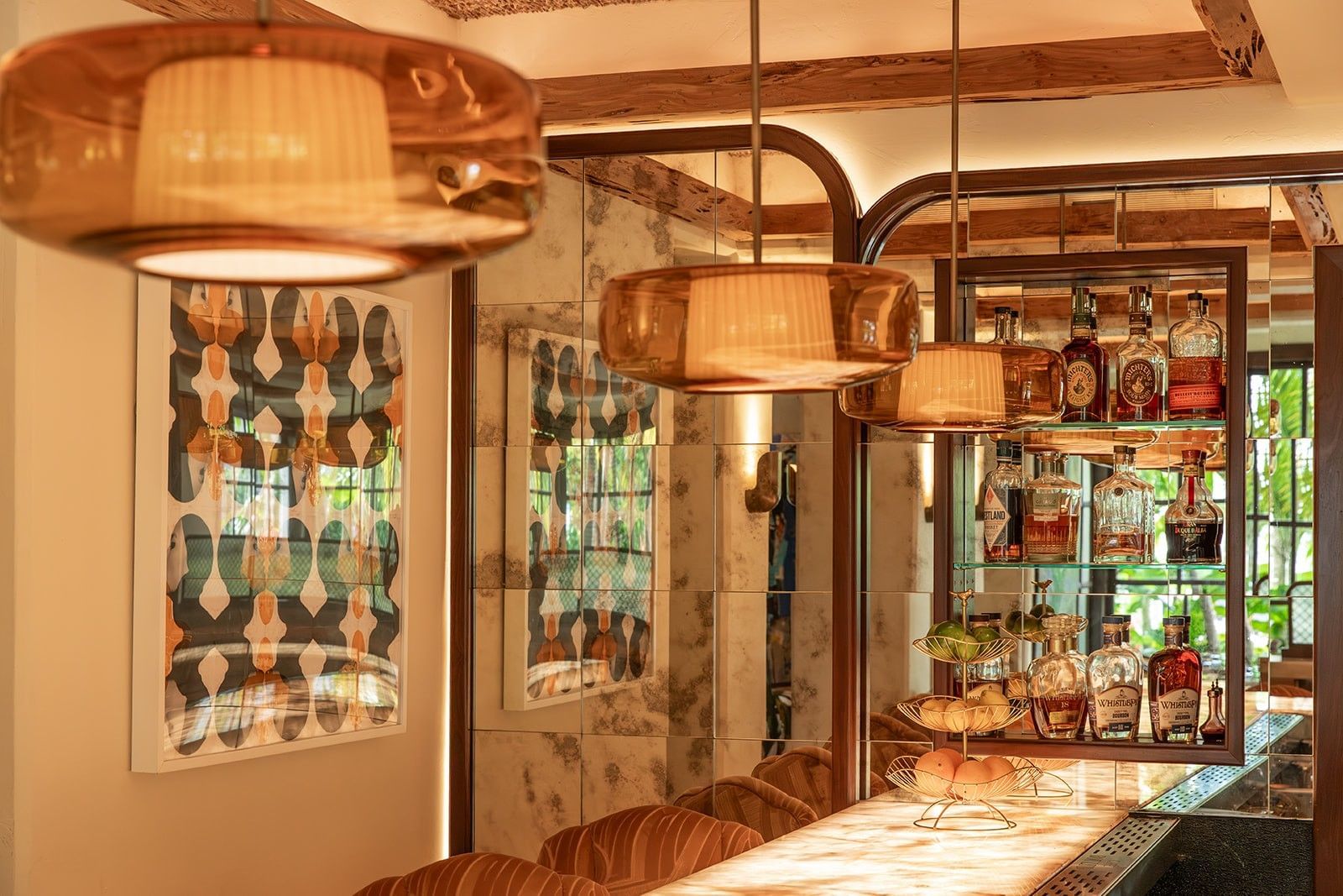 Elegant bar with wooden ceiling, mirrored walls, hanging lights, and shelves stocked with liquor bottles.