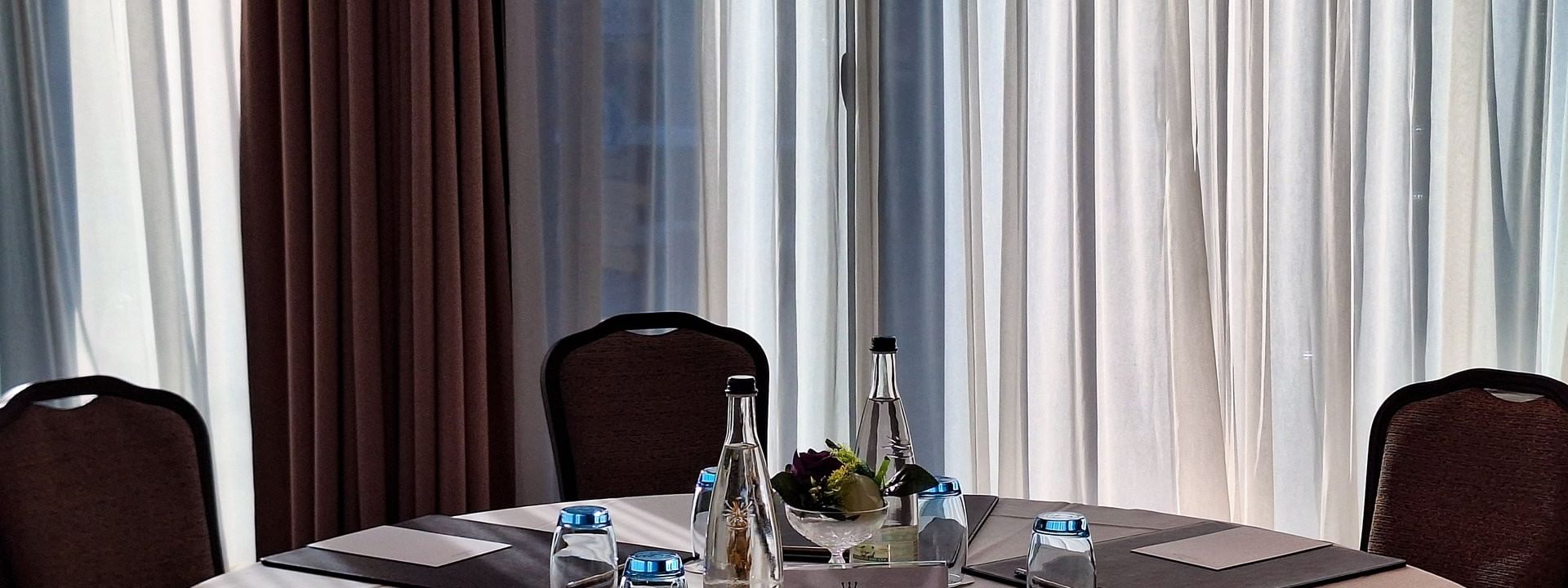 Padded chairs with rows by a long speaker table under a projector screen in Rigi + Cervin at Warwick Geneva