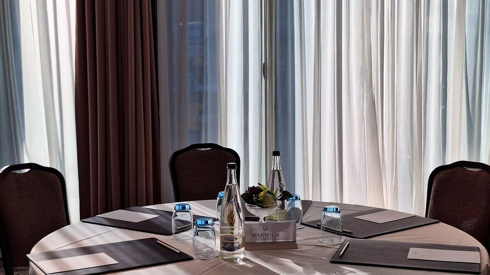 Padded chairs with rows by a long speaker table under a projector screen in Rigi + Cervin at Warwick Geneva