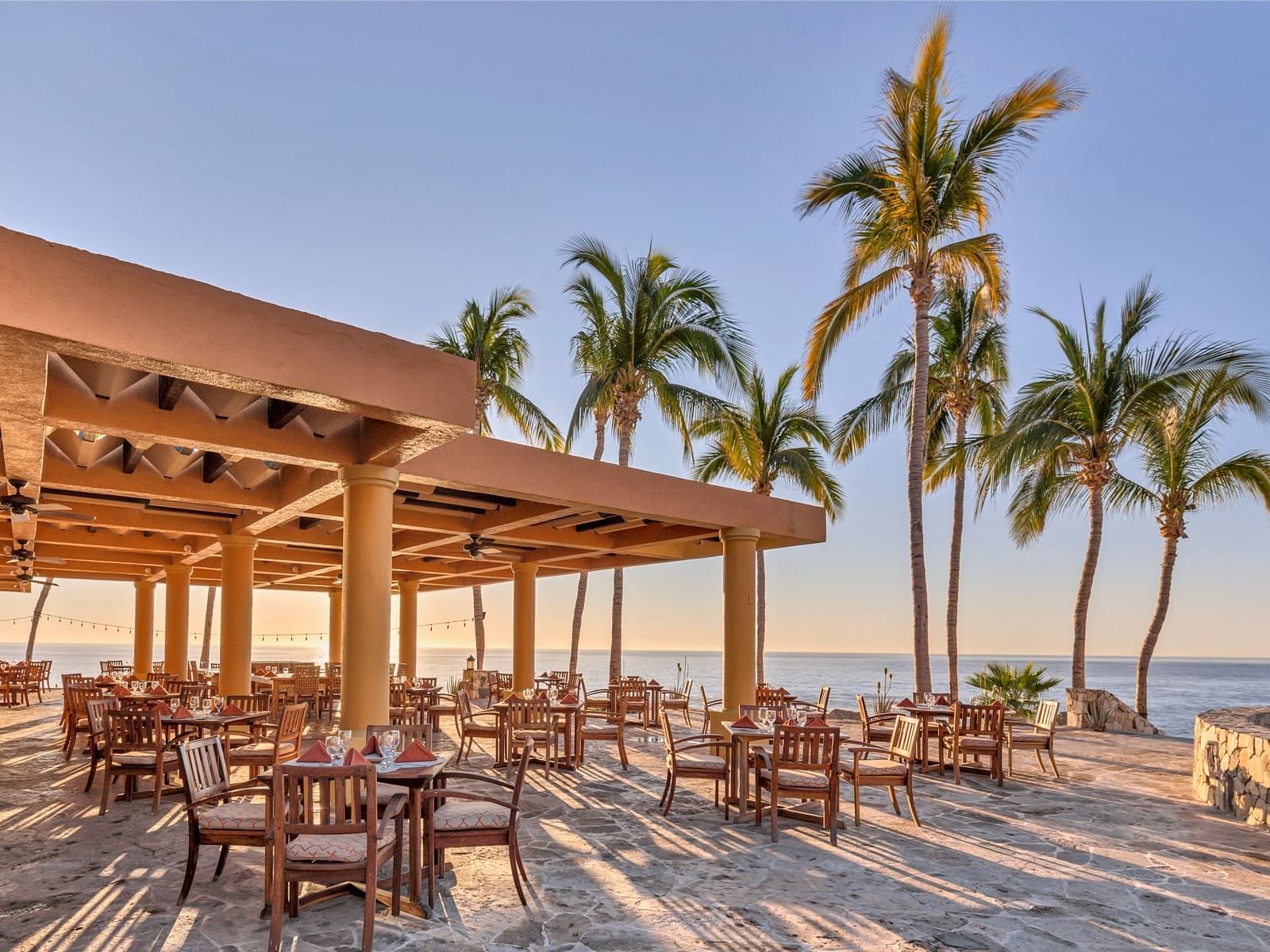 Outdoor dining tables by the beach at La Colección Resorts
