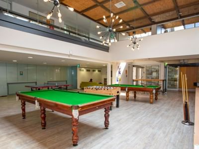 Large billiards room with three green tables and modern decor at La Trobe University - Chisholm College.