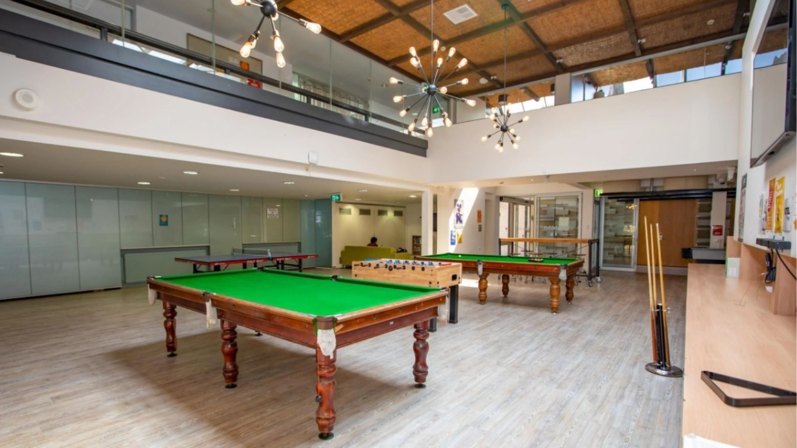 Large billiards room with three green tables and modern decor at La Trobe University - Chisholm College.
