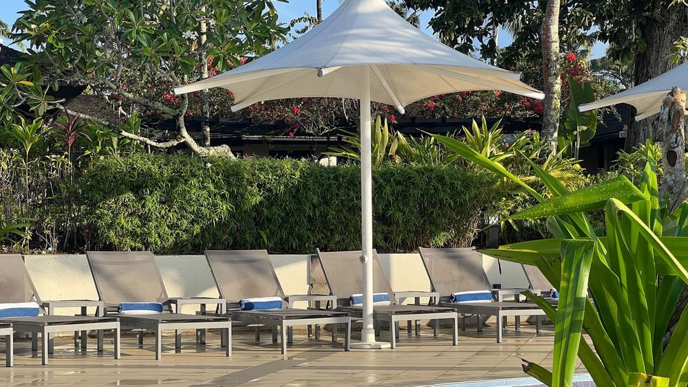 Umbrellas and lounge chairs by the pool and terrace beach at Warwick Le Lagon - Vanuatu in Efate.