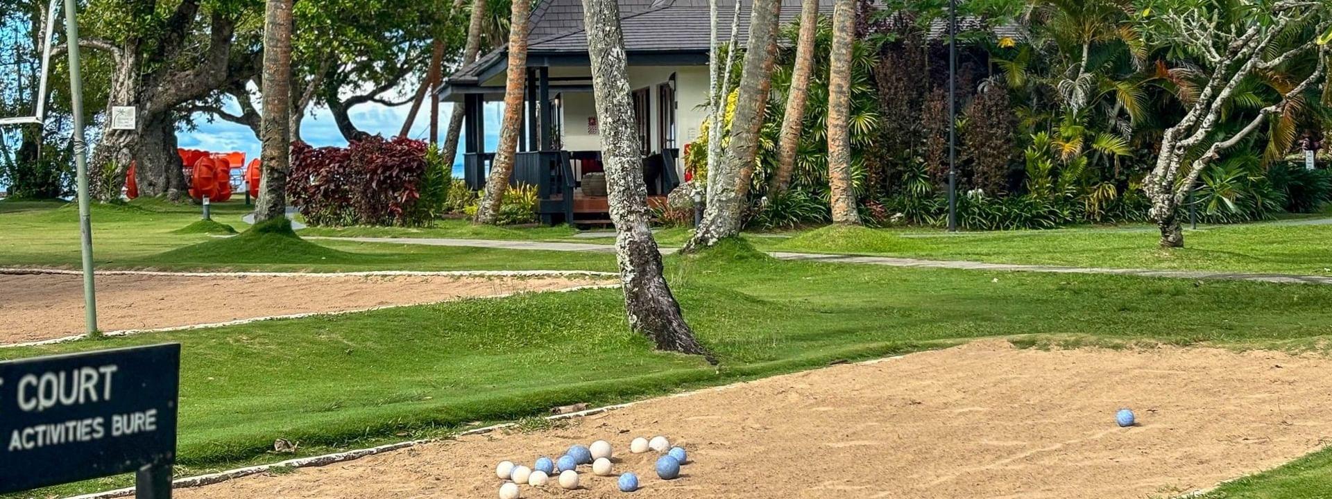 Boules court with balls scattered around and a house in the background at The Naviti Resort in Korolevu