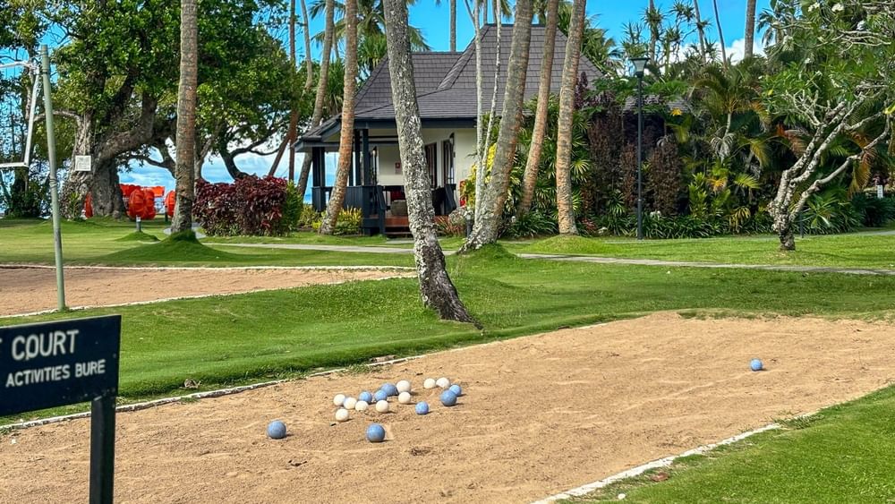Boules court with balls scattered around and a house in the background at The Naviti Resort in Korolevu.
