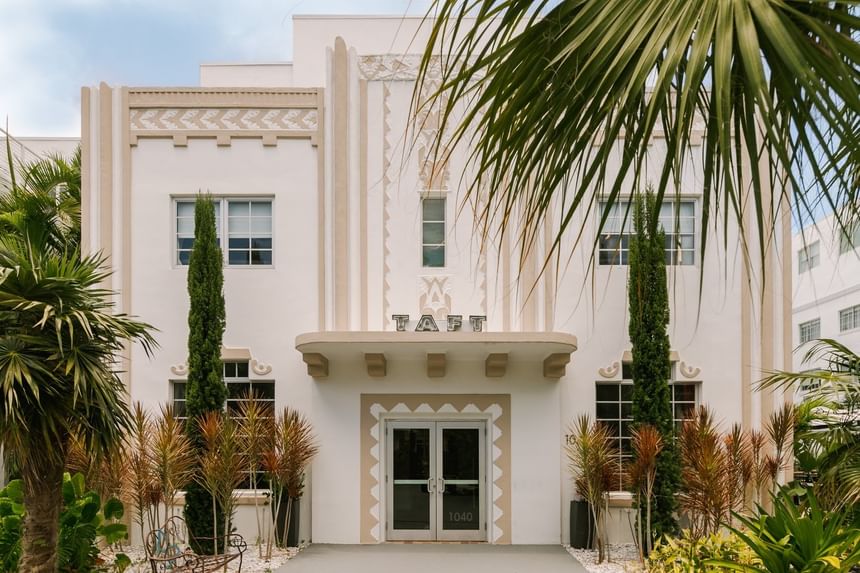Art Deco building facade with palm fronds and tropical landscaping at Kenmore Village Hotel, South Beach