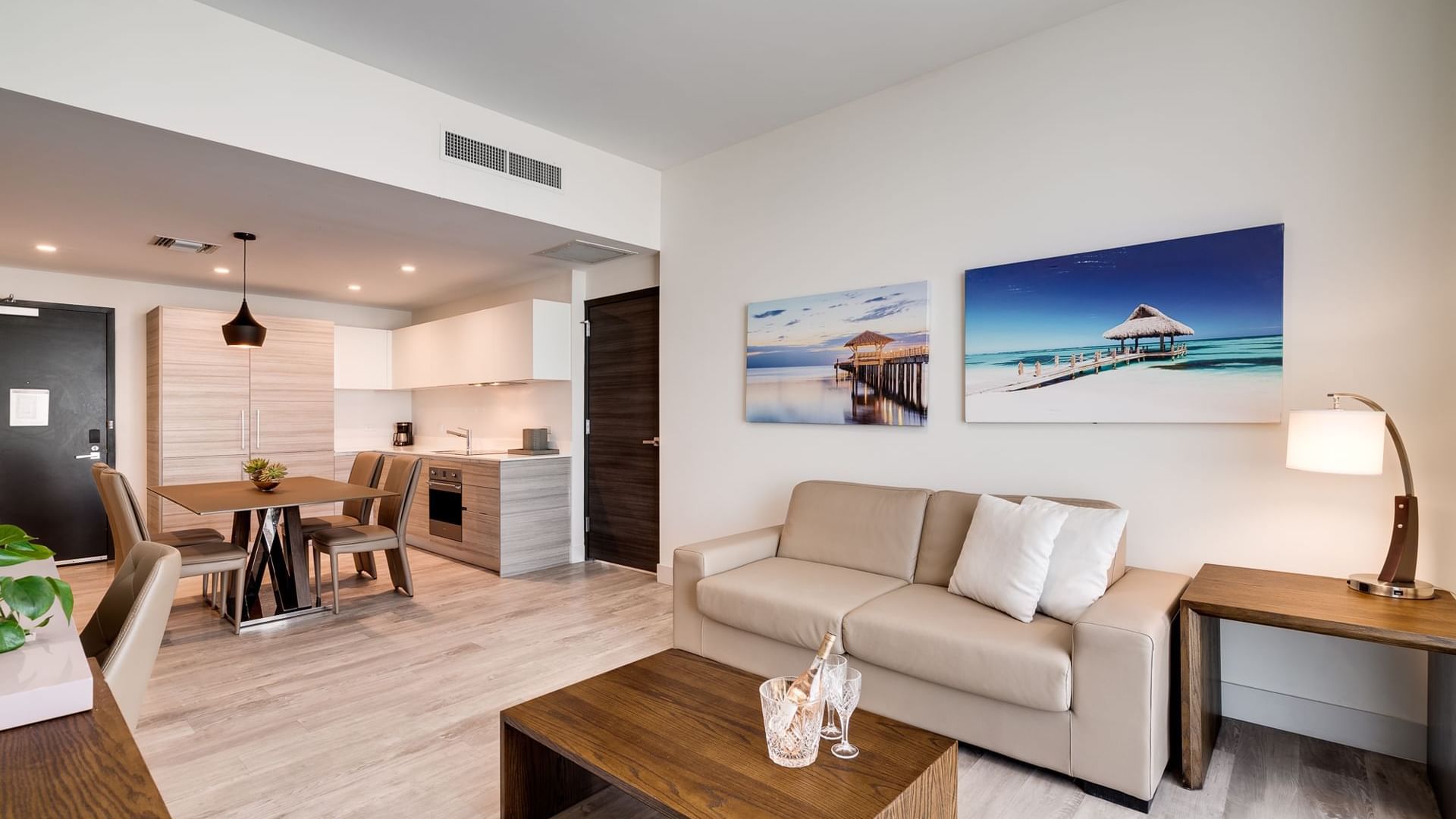 A modern living room with a sofa, coffee table, dining table, and kitchenette.