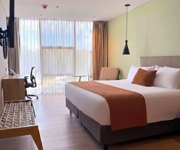 King bed facing wall-mounted TV near work area and sheer window in guest room at the Hotel B3 Sibelius