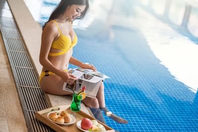 girl in yellow bikini sitting by the swimming pool