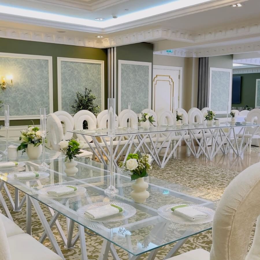قاعة جيمس مزينة بأناقة مع طاولات زجاجية وكراسي بيضاء في فندق ورويك الدوحة.