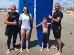 Family poses for a photo after a surf lesson in Diamond Beach near our Wildwood hotel