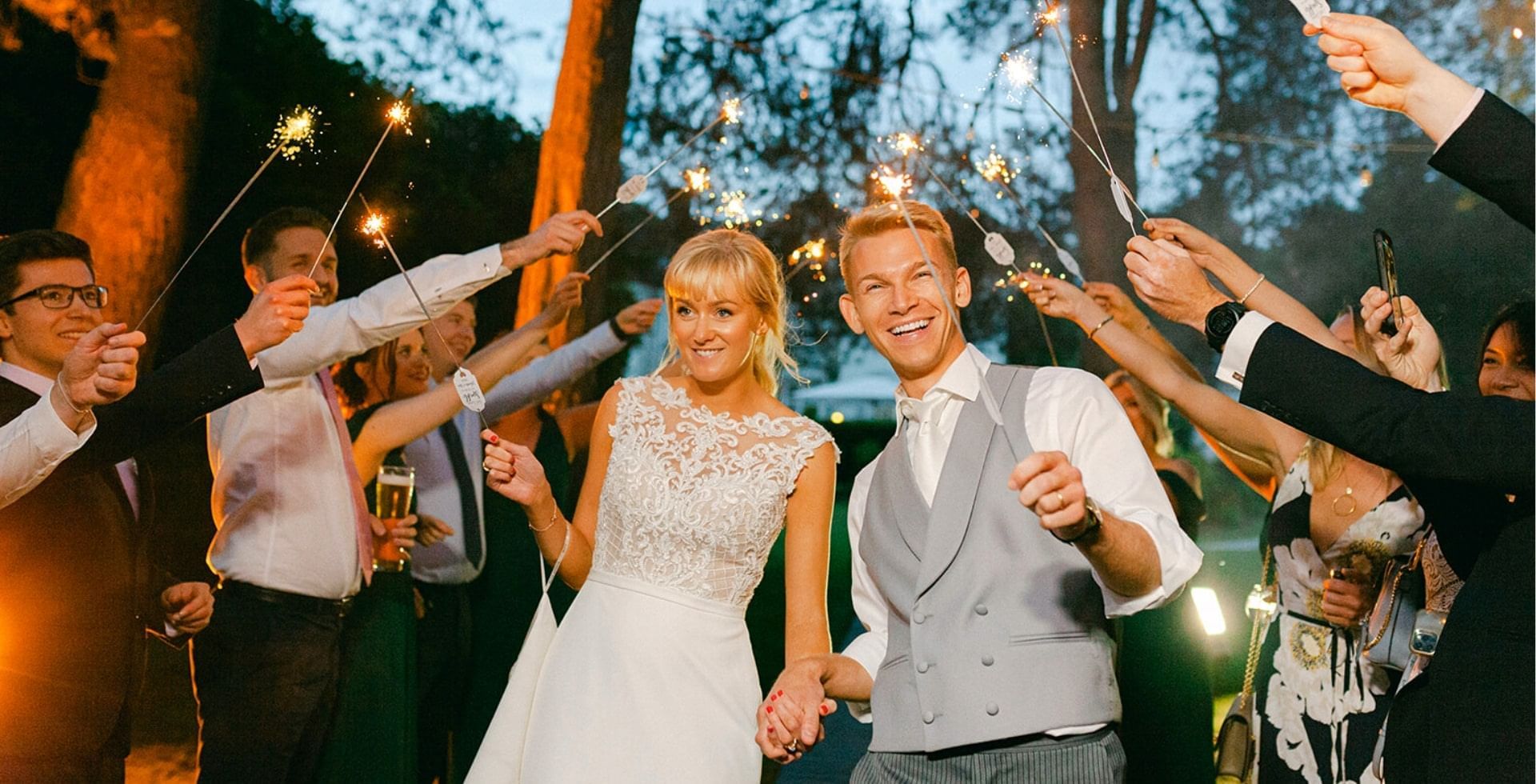 Bride, groom & gang holding sparkles in garden at Gorse Hill