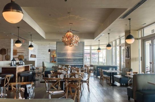 Indoor dining area with wooden chairs & globe pendant lighting in Wild Thyme Oceanside Eatery at The Atlantic Hotel & Spa