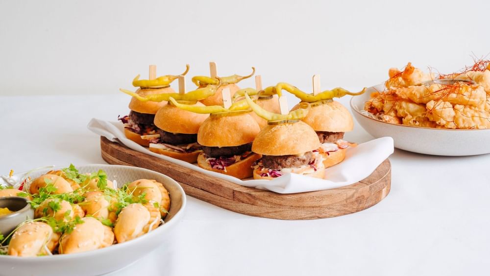 Assortment of appetizers featuring mini sliders, crispy shrimp, & empanadas in The Lounge at Novotel Sydney Olympic Park
