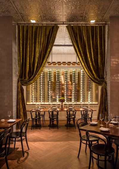 Private meeting room with tables and a lit wine display backdrop at Hotel Bijou, featuring San Francisco event venues