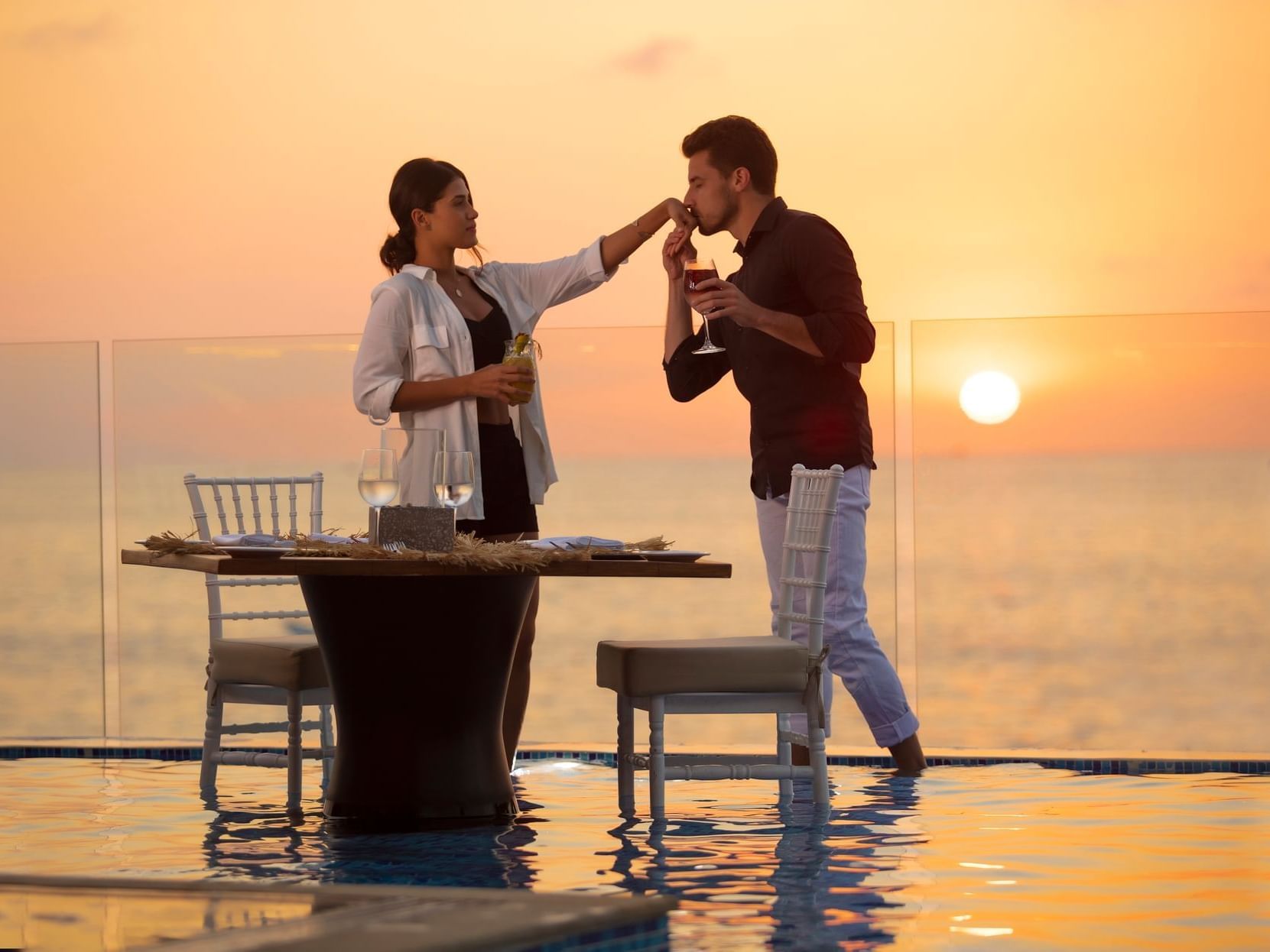Couple enjoying a meal on a balcony at sunset, Los Arcos Suites