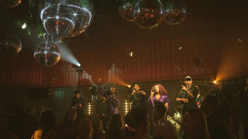 Band performing on stage with disco balls and spotlights at an event in the Ballroom at The Londoner Hotel