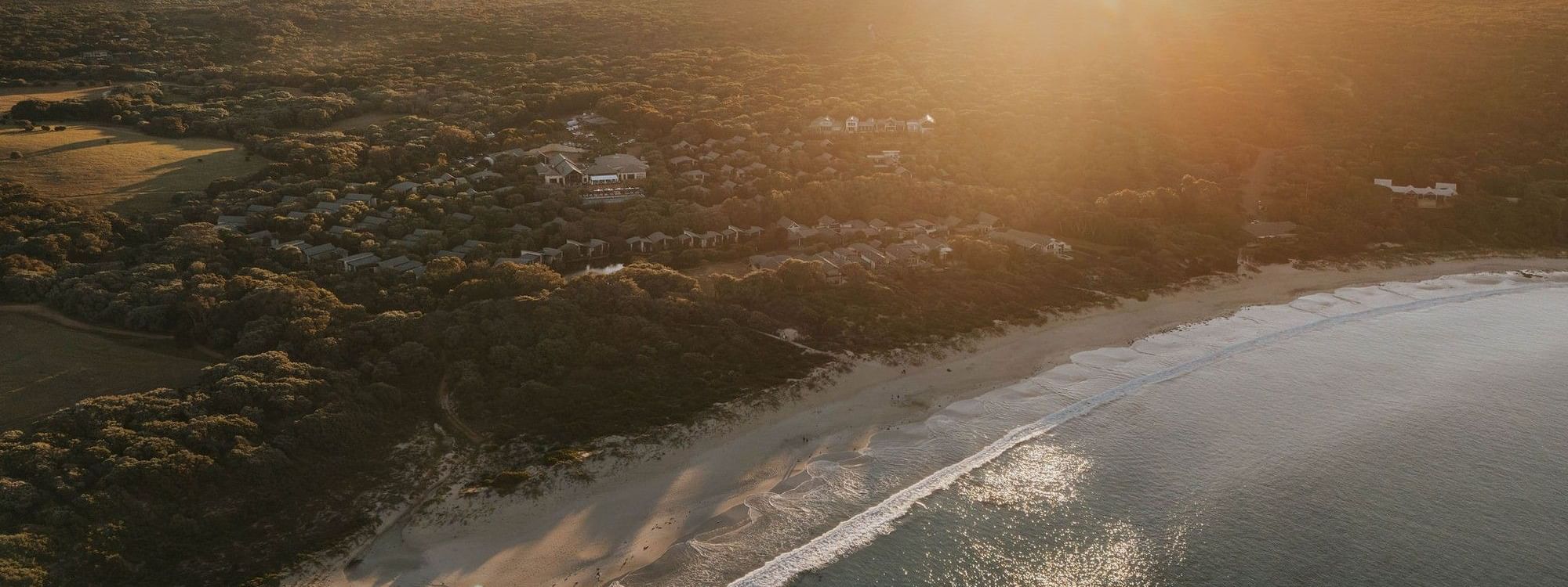 Sunset over coastal resort with beach and ocean view, highlighting Winter Wellbeing Meeting Offer.
