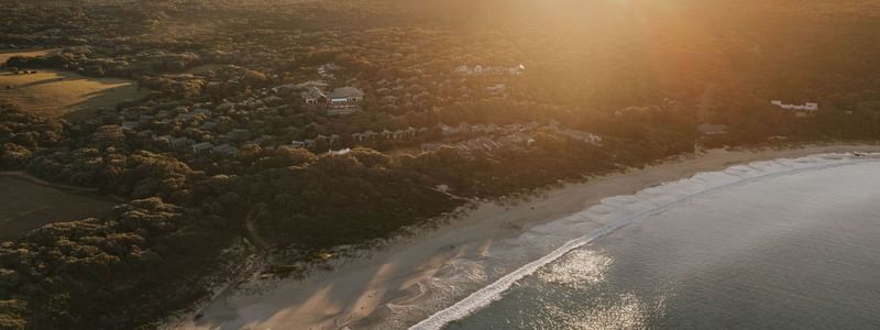 Sunset over coastal resort with beach and ocean view, highlighting Winter Wellbeing Meeting Offer.