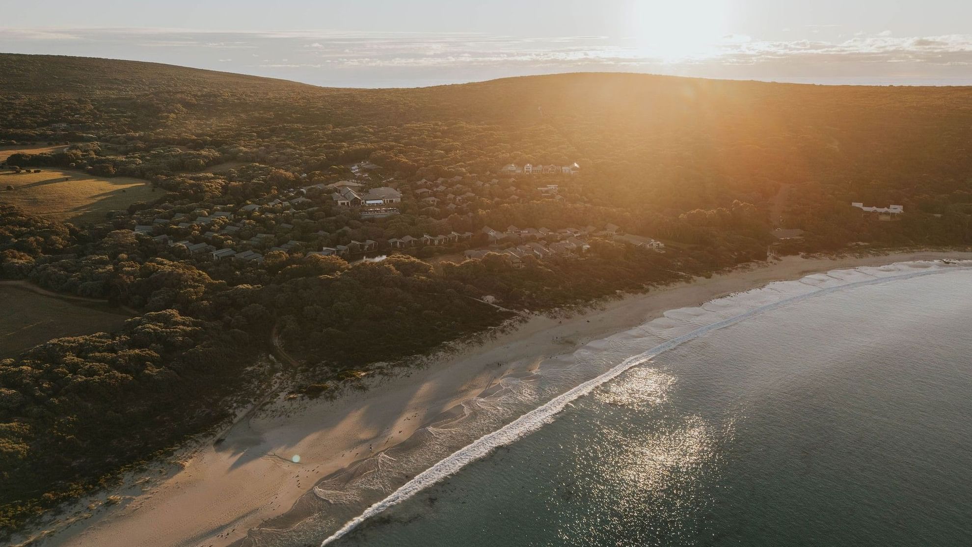Sunset over coastal resort with beach and ocean view, highlighting Winter Wellbeing Meeting Offer.