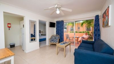 One-bedroom living room with a blue couch and coffee table facing a patio balcony view at Worthing Court Apartment