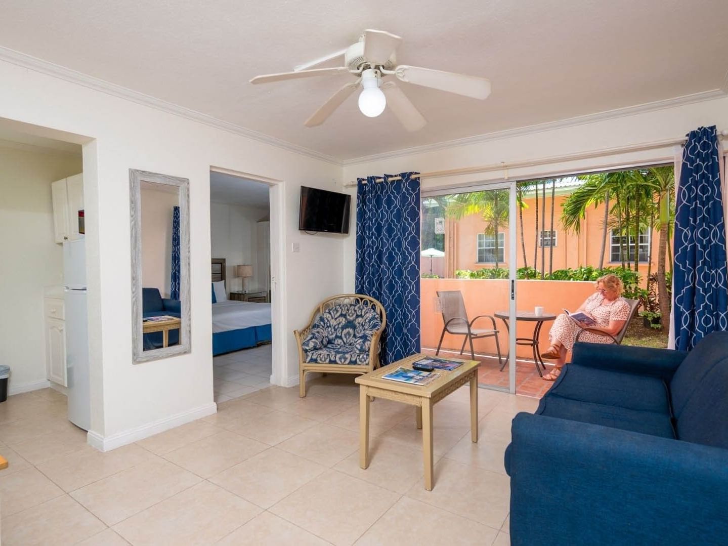 Bright suite living area with blue sofa and patio doors overlooking a garden terrace at Worthing Court Apartment