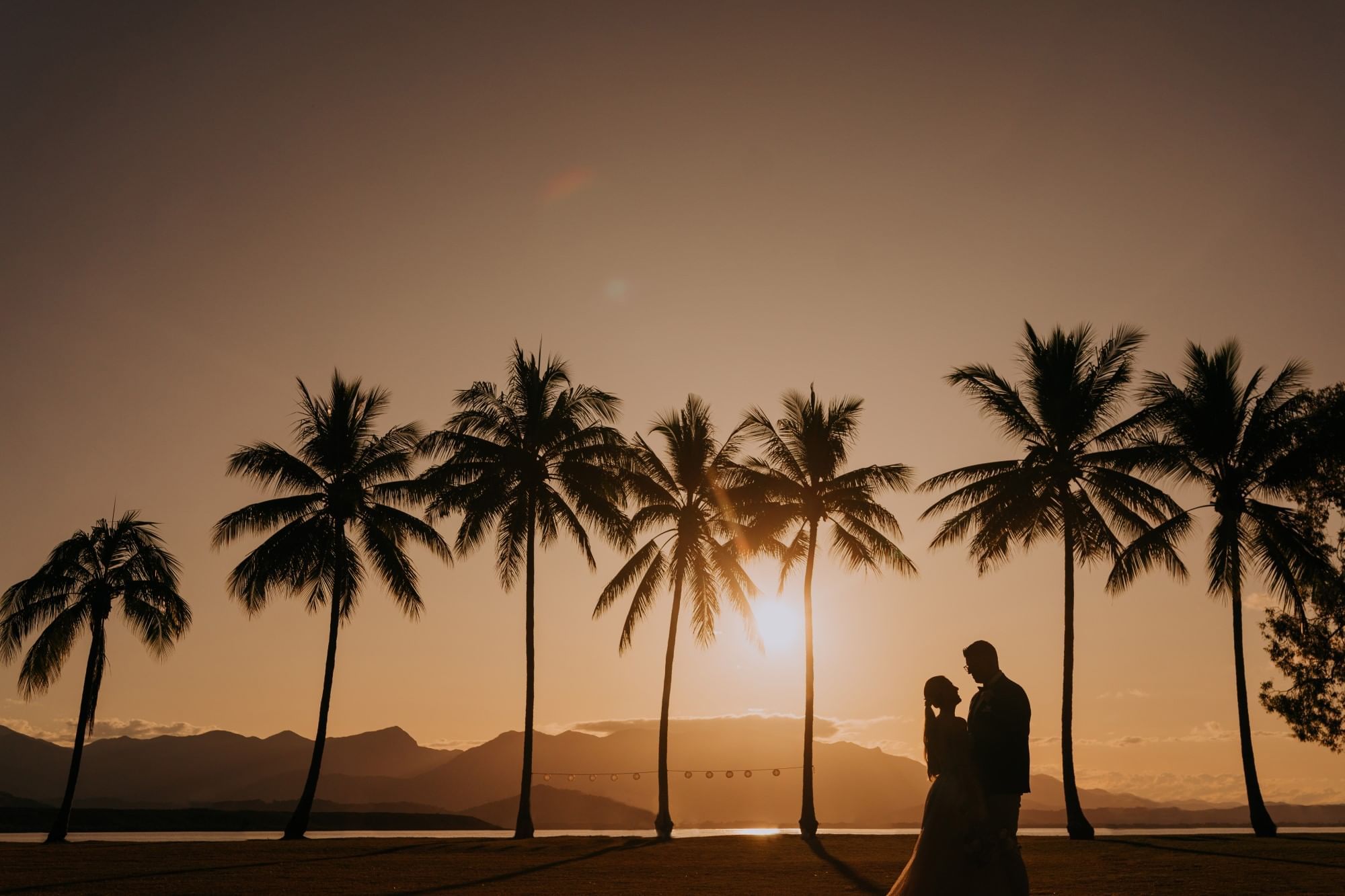 Silhouette of wedded couple under palm trees in sunset at Pullman Port Douglas Sea Temple Resort & Spa
