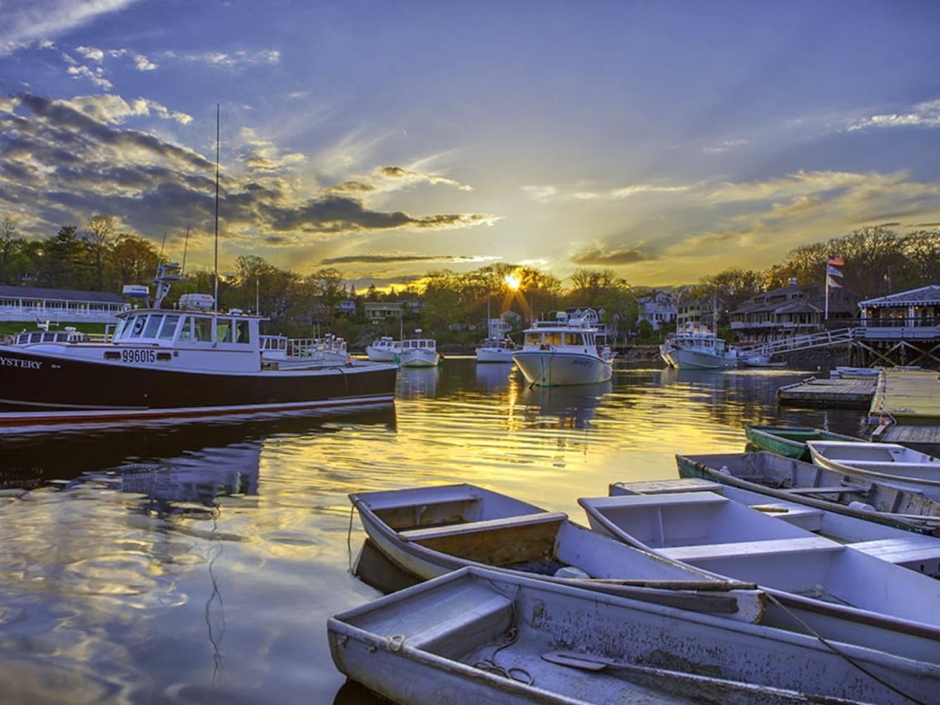 Boats docked at sunset with the sun setting behind them at Perkins Cove near Anchorage by the Sea